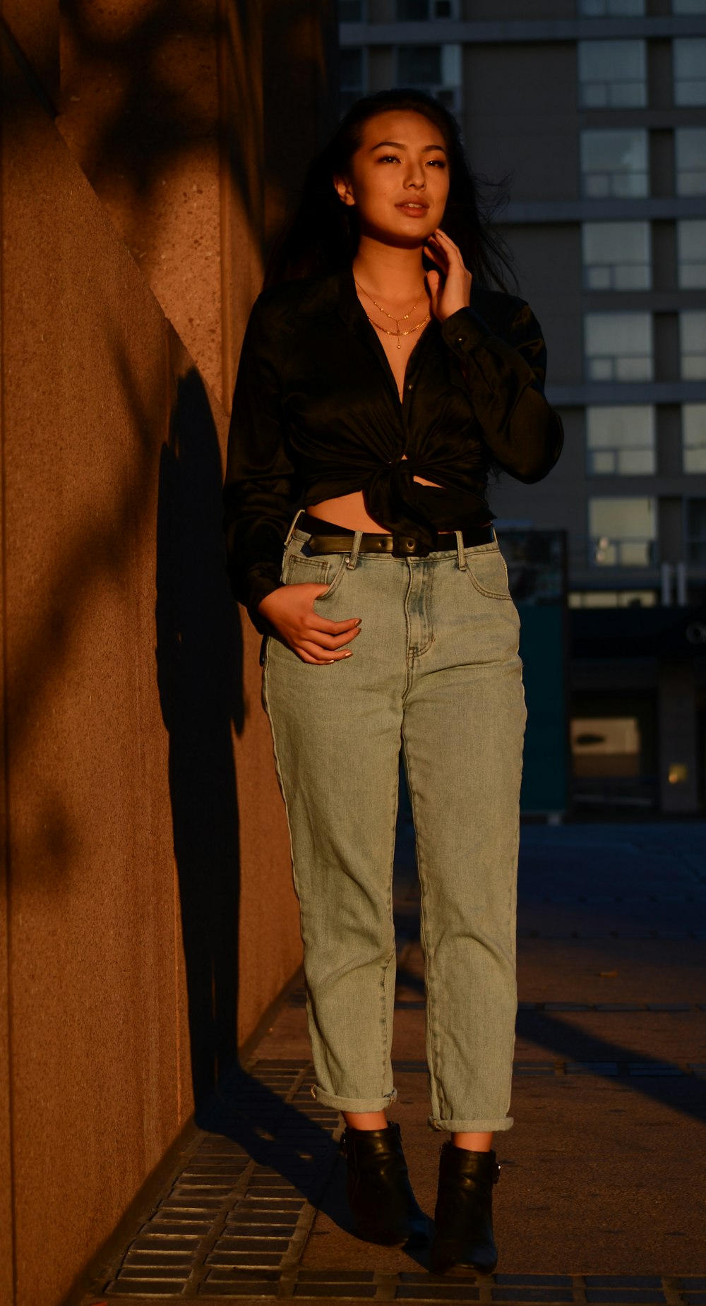 woman wearing black self-tie top beside wall