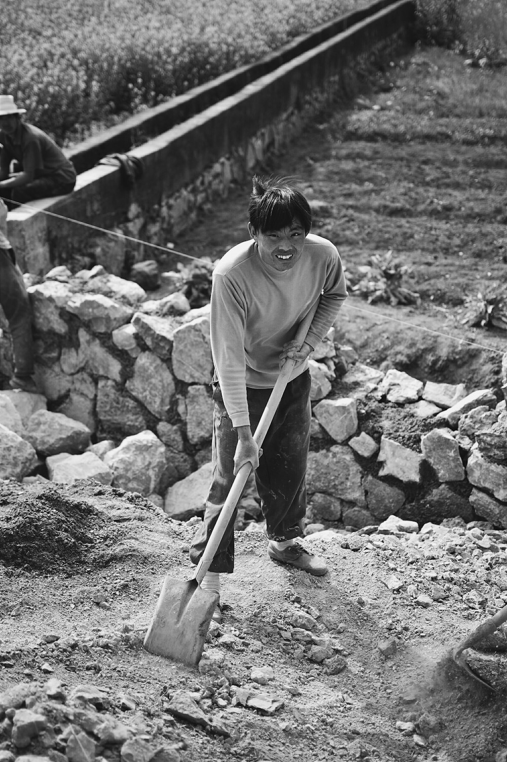 grayscale photo of man holding shovel