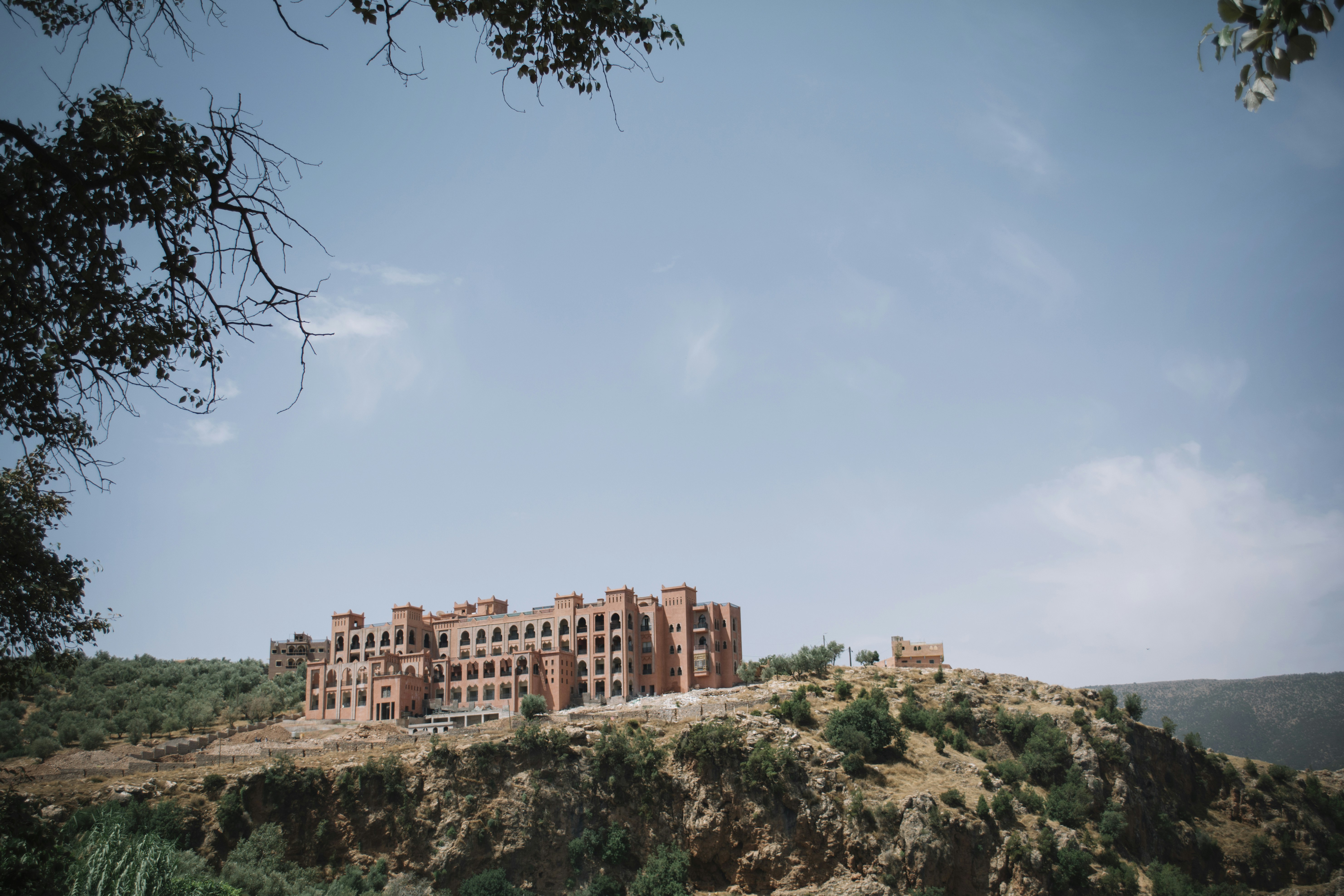 brown multi-story concrete building on cliff during daytime, Wes Anderson in Morocco
