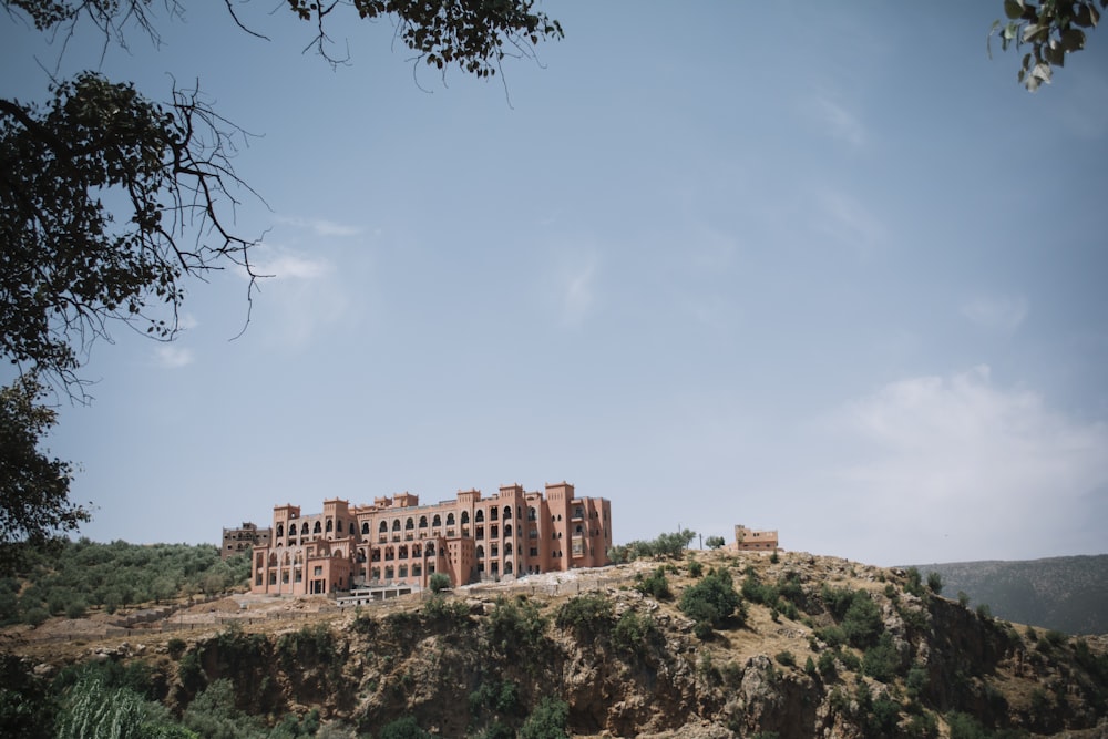 brown multi-story concrete building on cliff during daytime