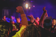 Guests raising their hands in excitement as colorful lights pulse through the room.