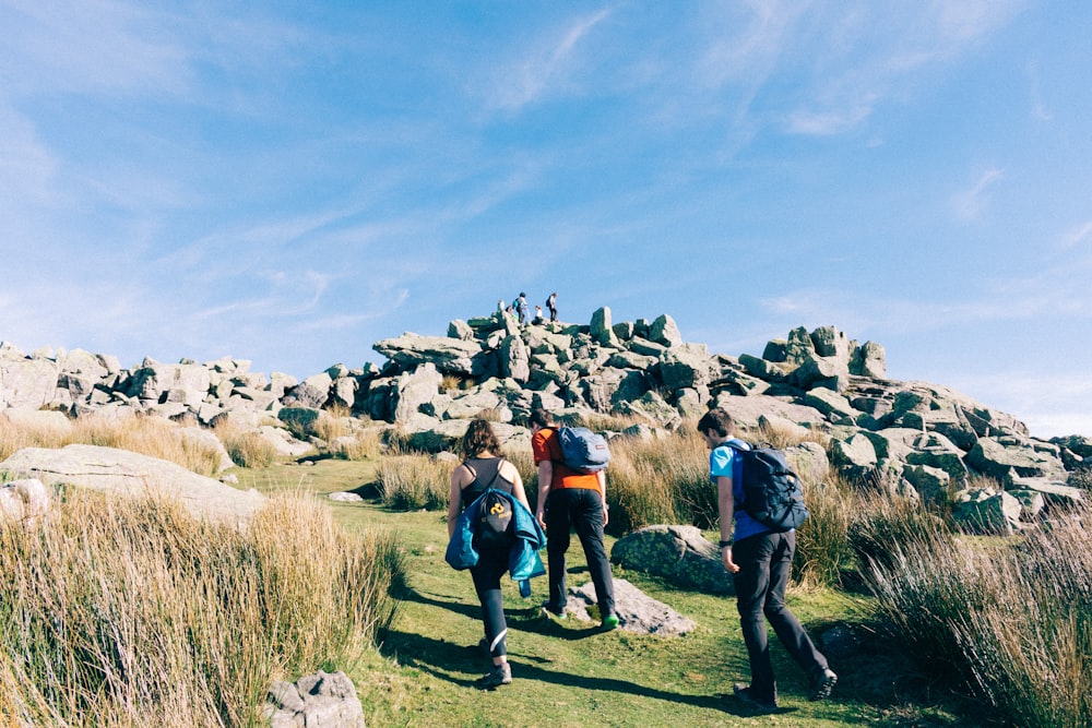 three person walking on uphill during daytime