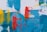 An abstract painting features bold and vivid brushstrokes. Shades of blue create a textured background, overlaid with vibrant red vertical patterns resembling wire or grid structures. Yellow streaks add contrast and dynamic energy to the composition.