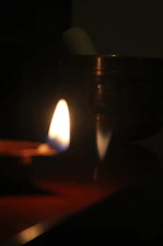 A glowing yantra symbol surrounded by softly flickering candles in a dark room.