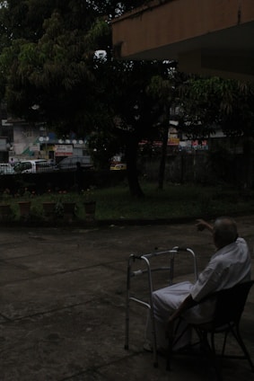 A smiling elderly person comfortably seated in a sleek, sturdy wheelchair outdoors on a sunny day.