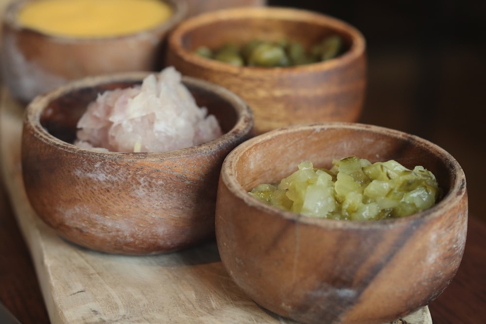 four brown bowls with foods