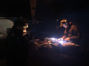 Close-up of a DJ spinning records with a crowd illuminated by charcoal and neon lights.
