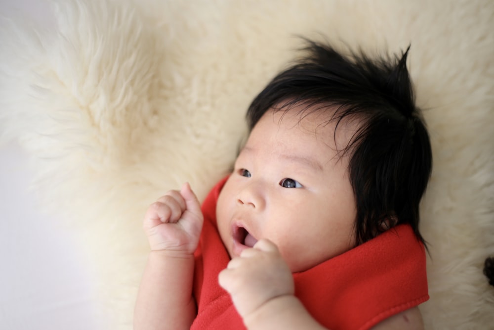 Selektive Fokusfotografie eines Babys, das ein rotes Oberteil trägt