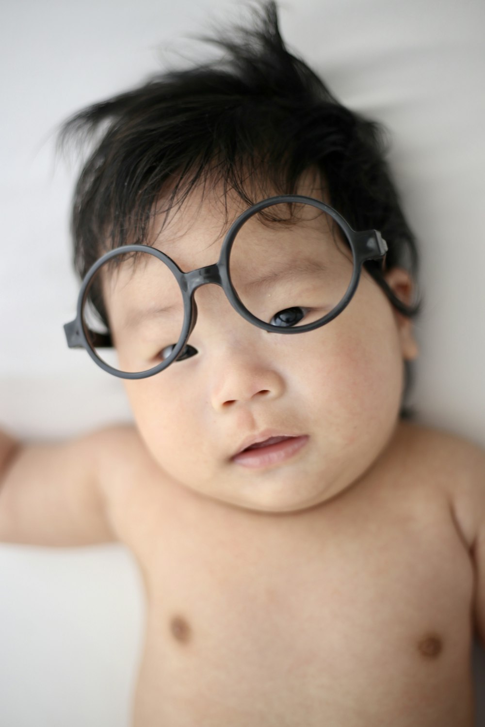 baby lying on white cloth