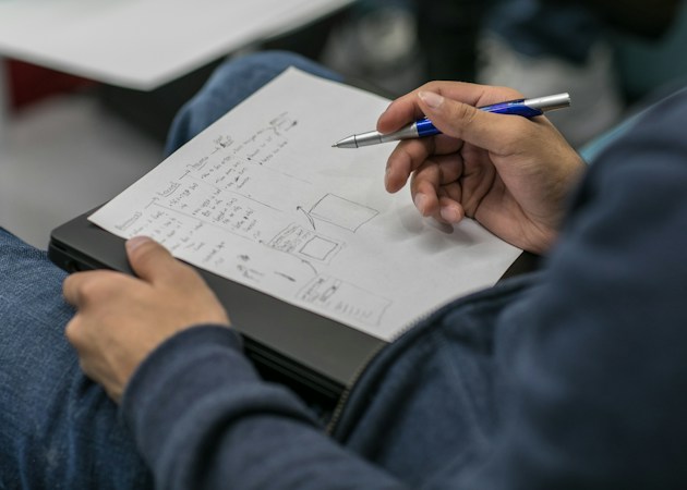 A person writing answers on a paper test form