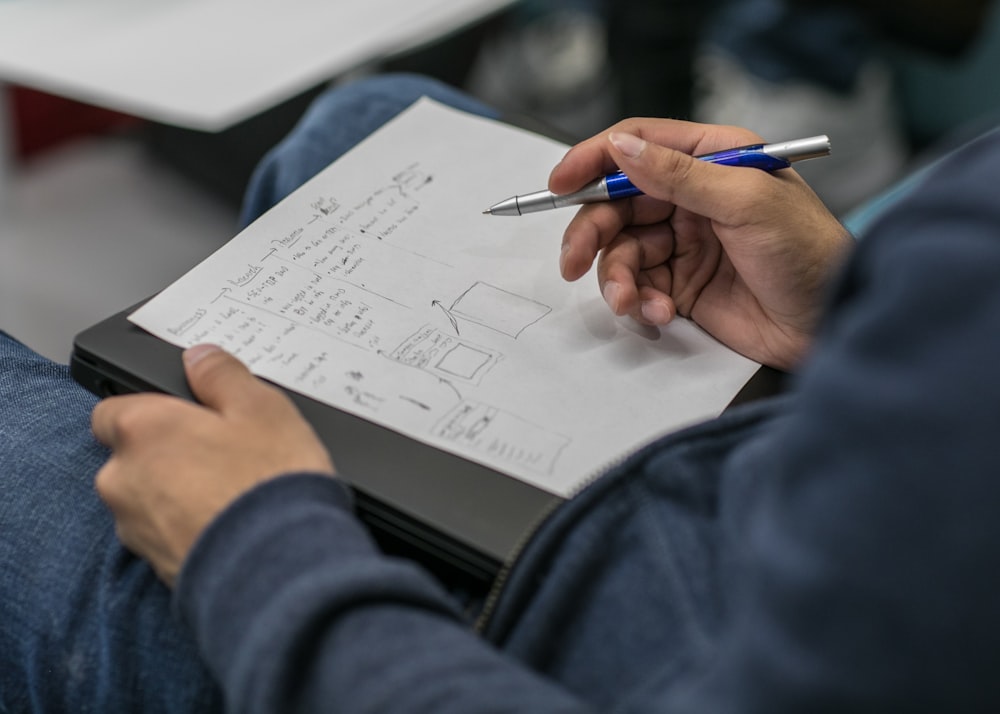 person writing on paper at lap