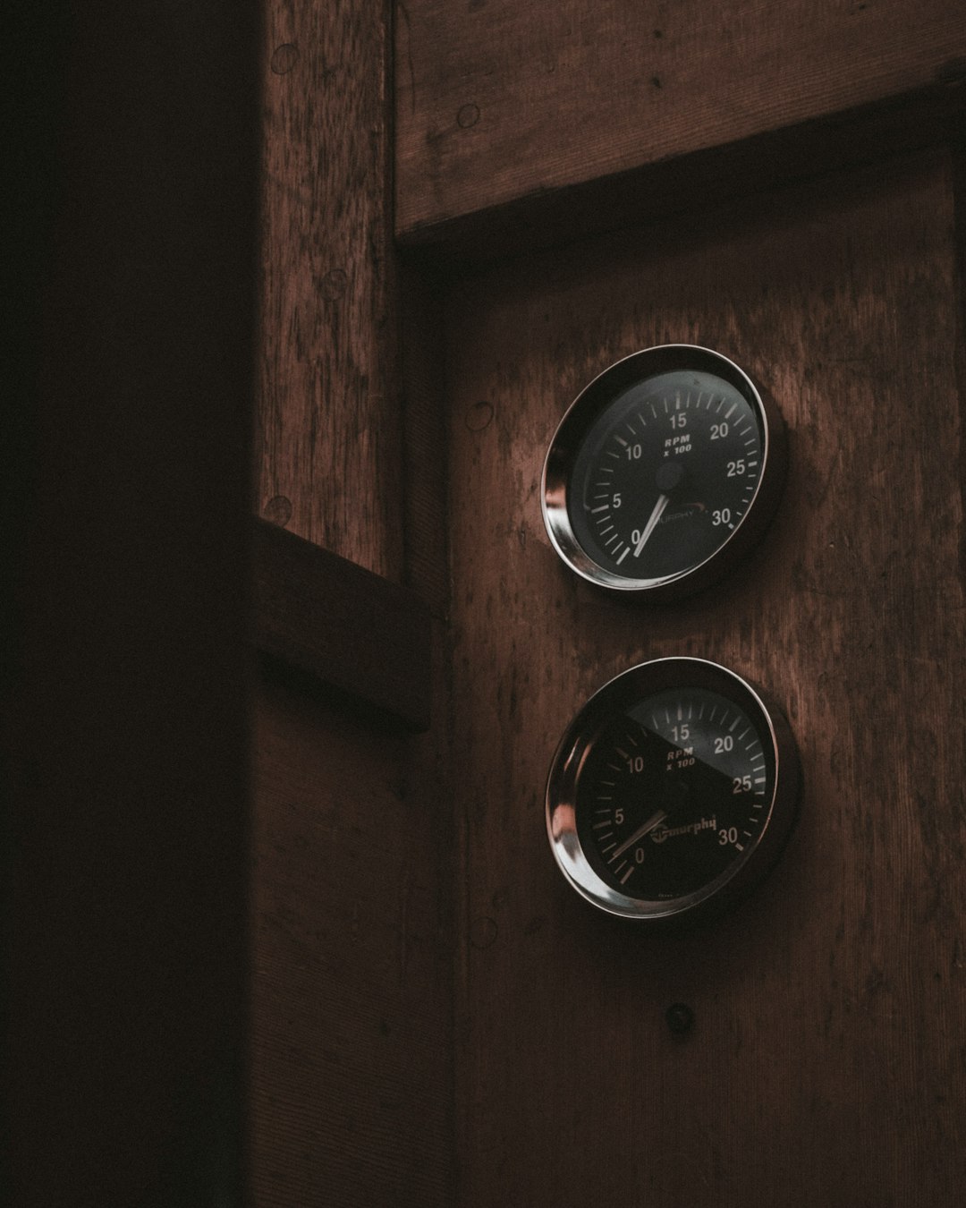 two analog gauges on brown wooden surface