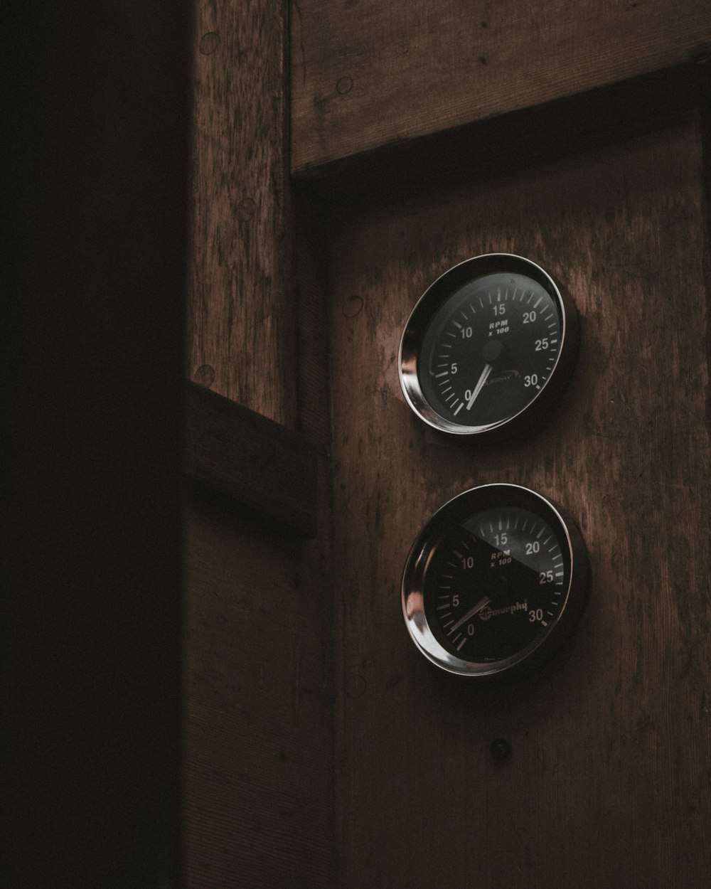 two analog gauges on brown wooden surface