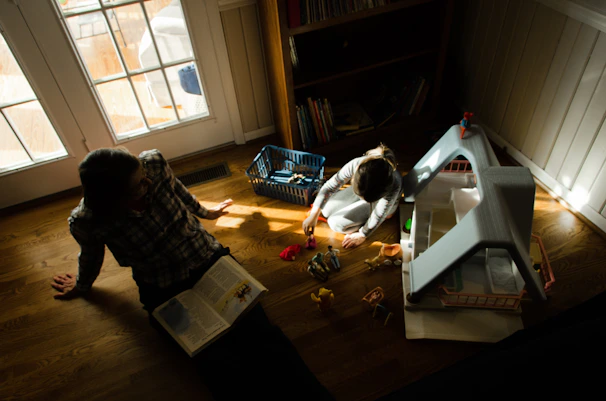 A cozy family reading together in a sunlit living room filled with children's books and toys.