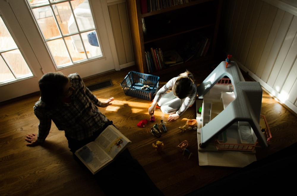 sitting man reading book beside boy playing toy