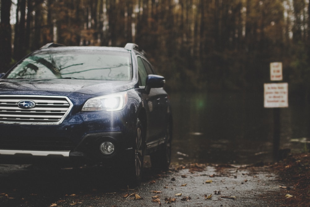 blue Subaru parked near forest