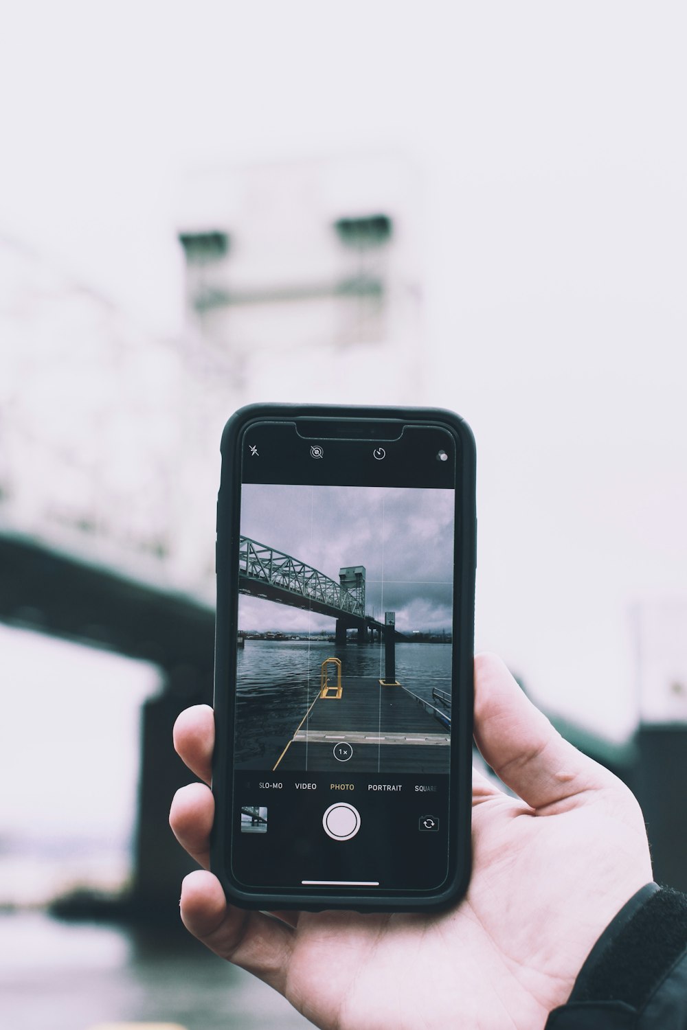 person holding black smartphone taking photo of bridge