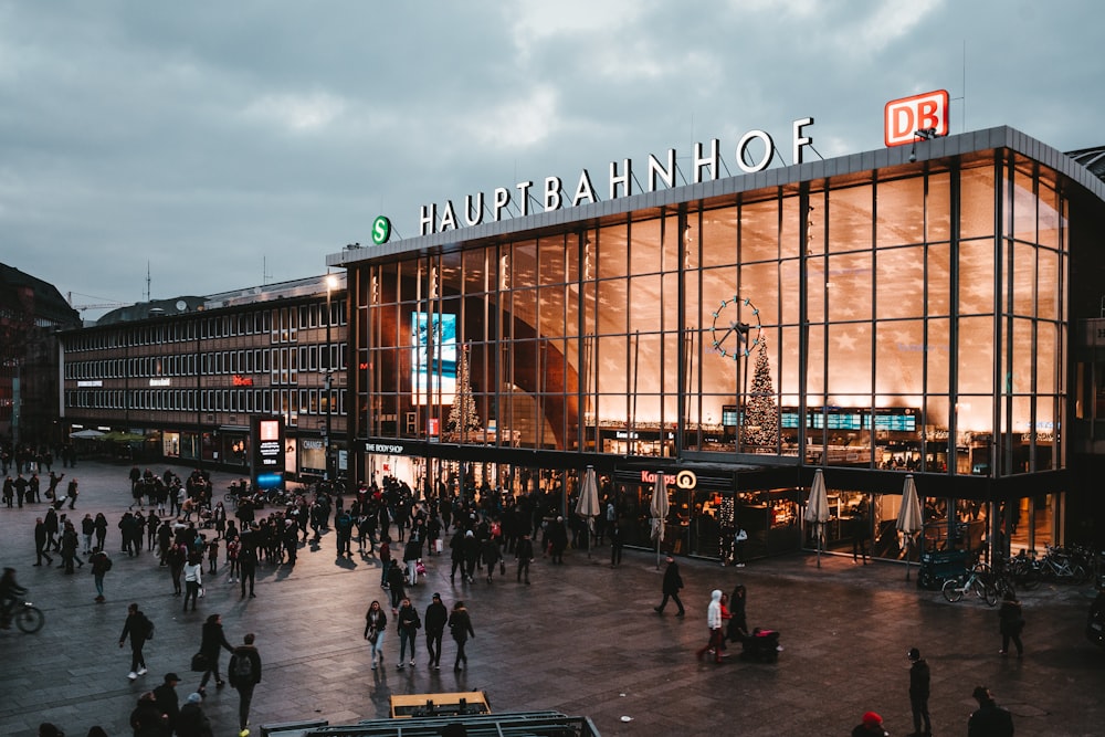 people walk in front of Hauptbahnof building under cloudy skies