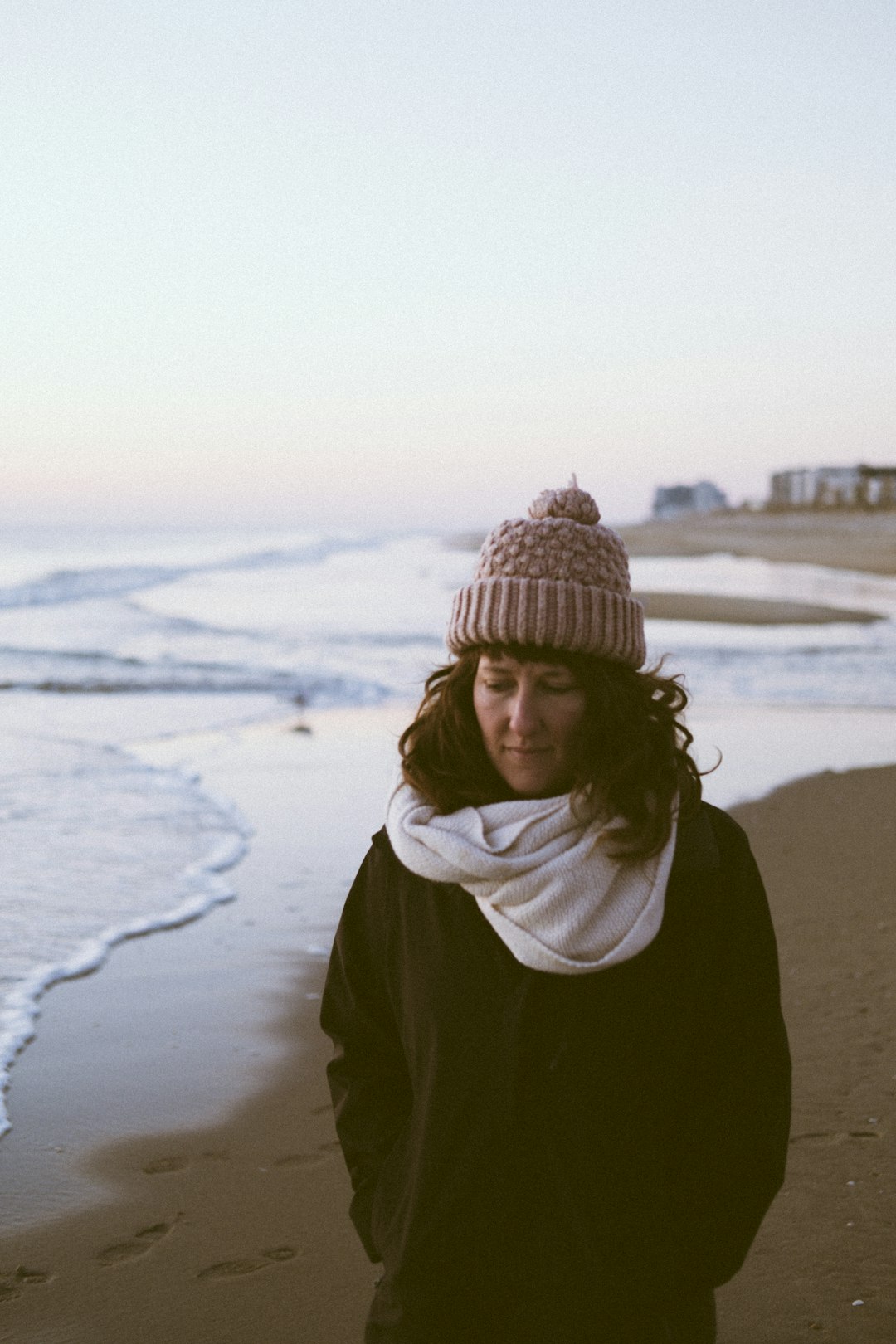 woman wearing brown beanie and white scarf on seashore during daytime