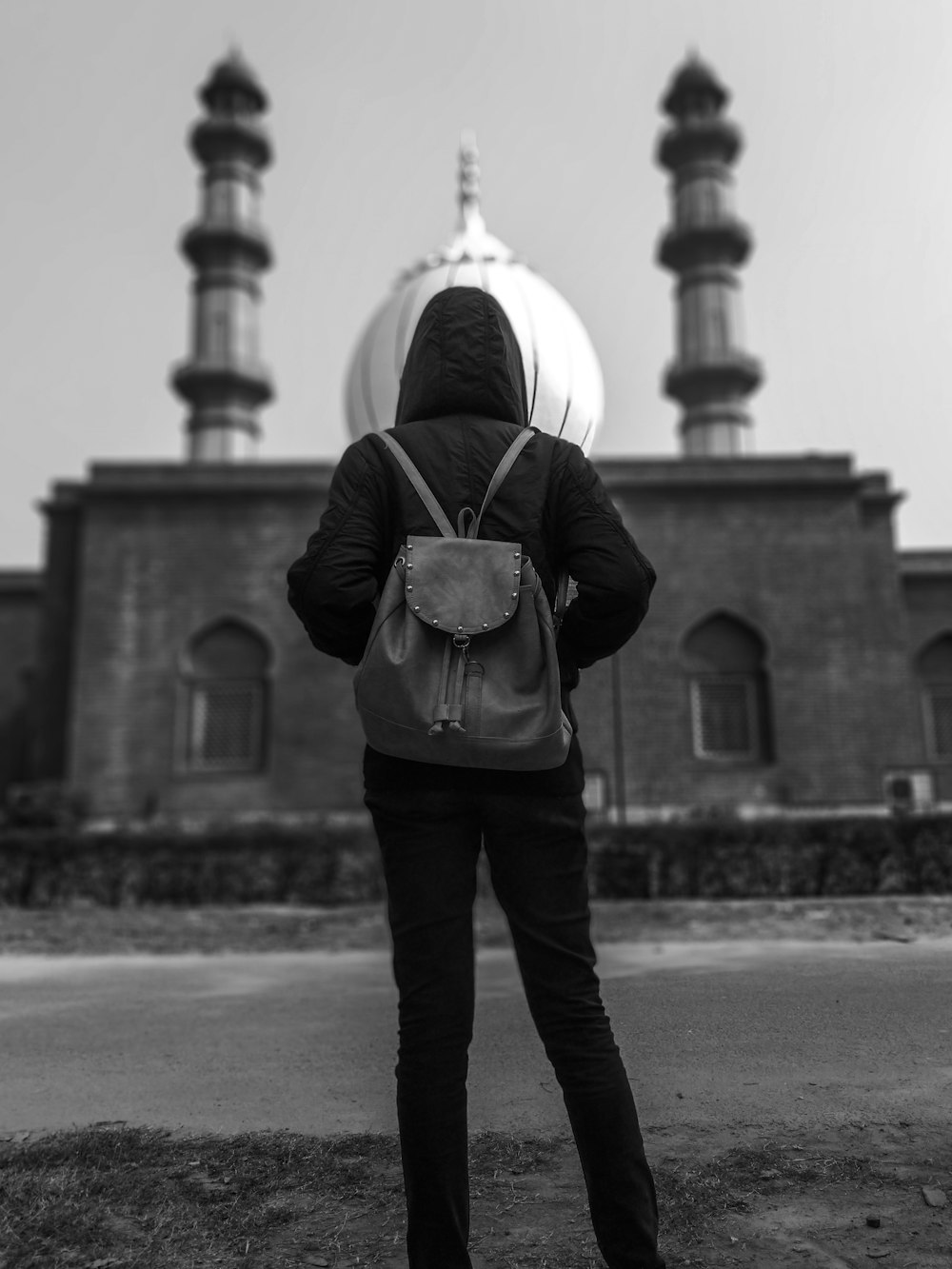 grayscale photography of man standing near mosque