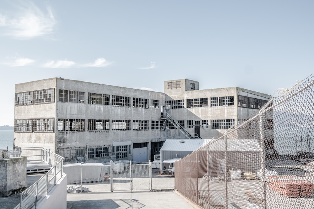 white concrete building front of iron wire fence at daytime