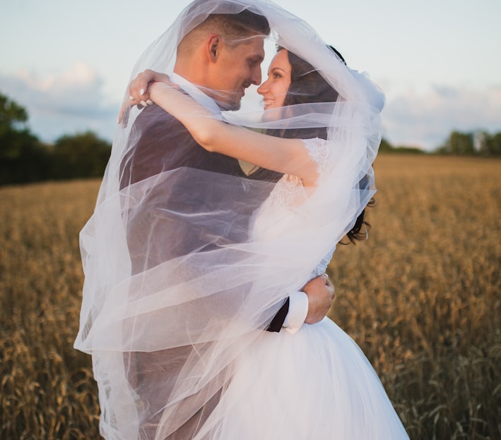 smiling newly wed couple about to kiss in green field