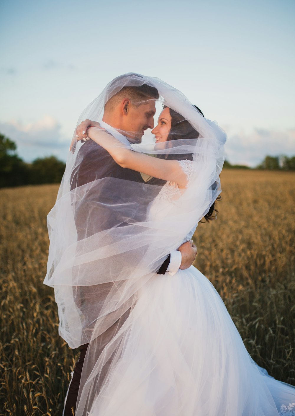 sonriente pareja de recién casados a punto de besarse en campo verde