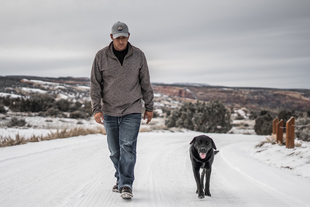 Hombre caminando junto a un perro negro durante el día