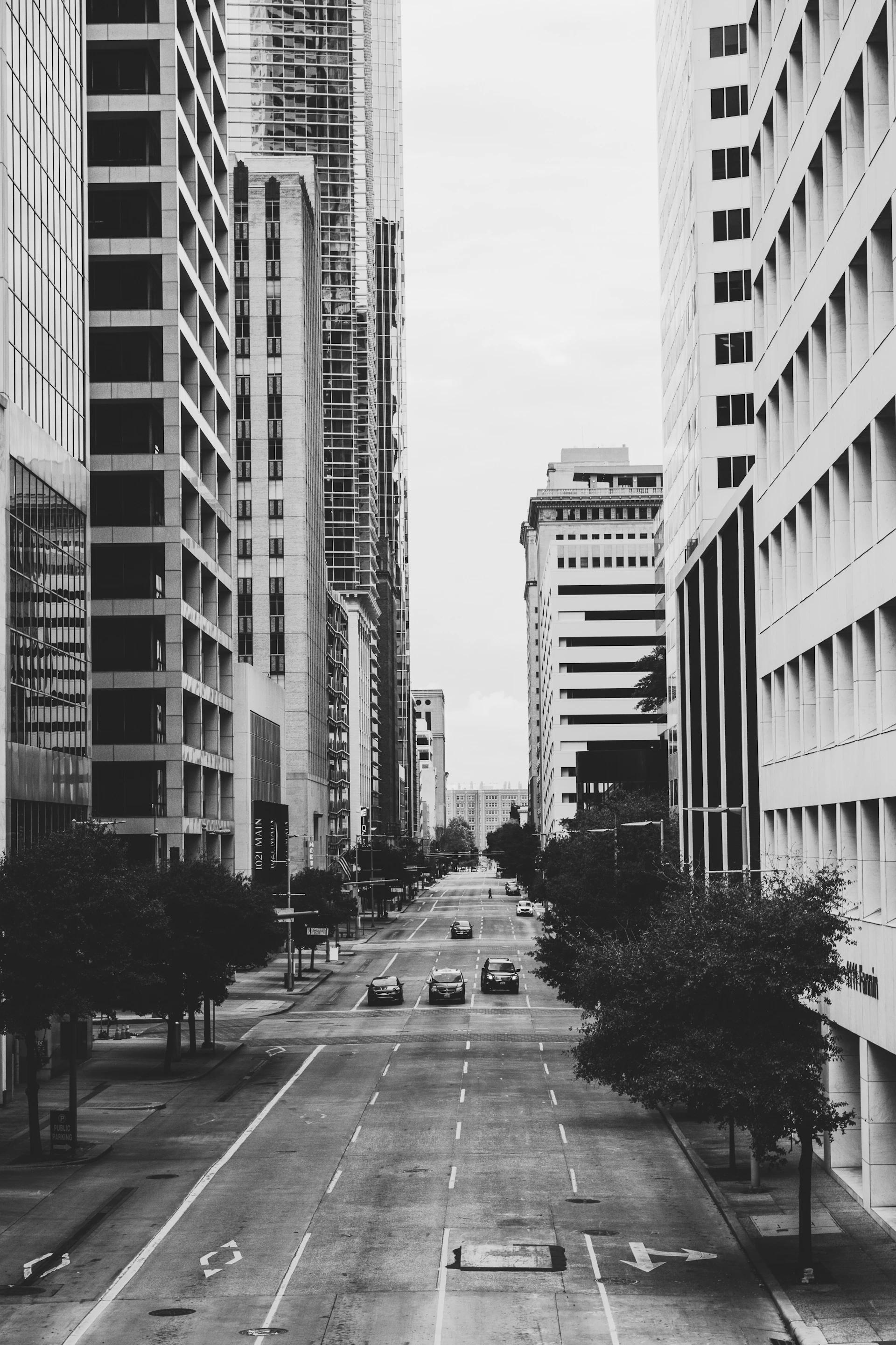 grayscale photo of vehicles on road and buildings