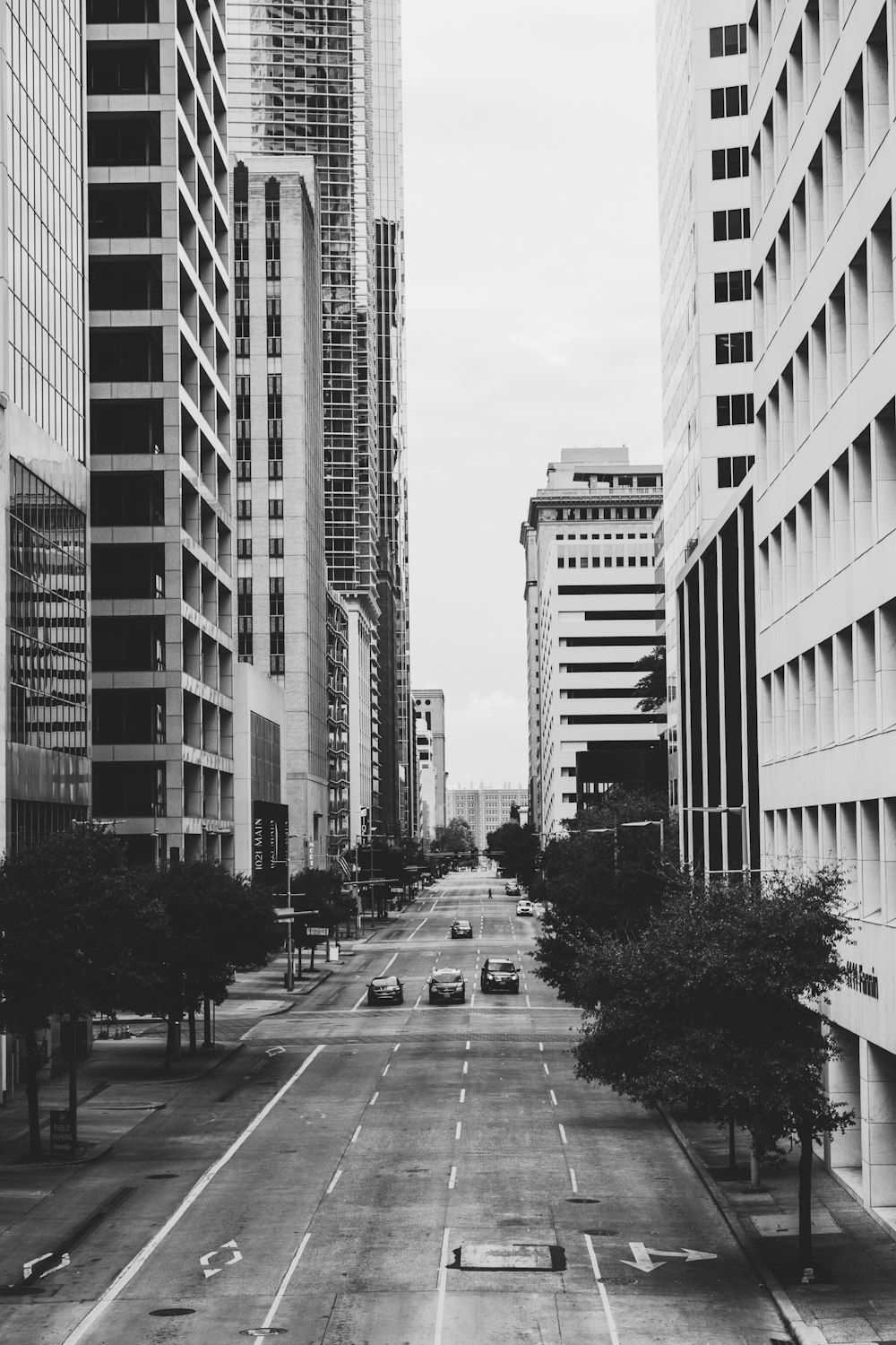 grayscale photo of vehicles on road and buildings