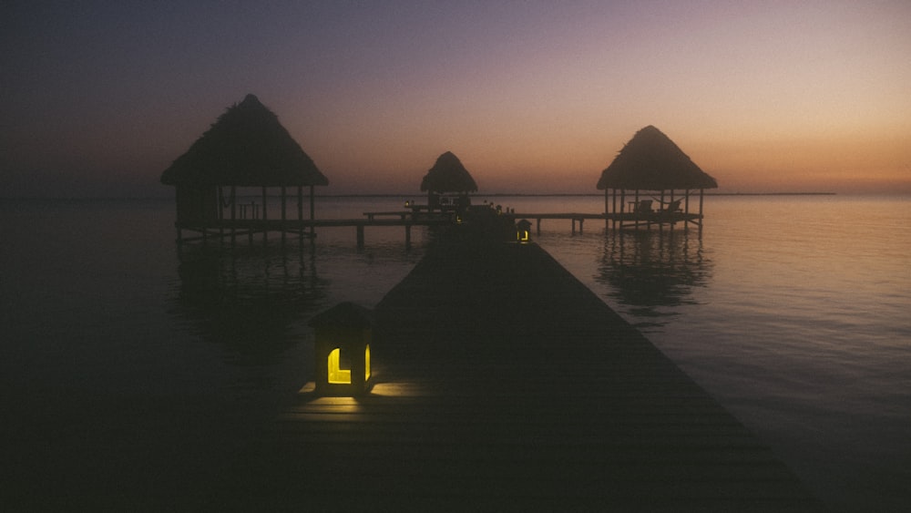 three brown huts on body of water photo during dawn