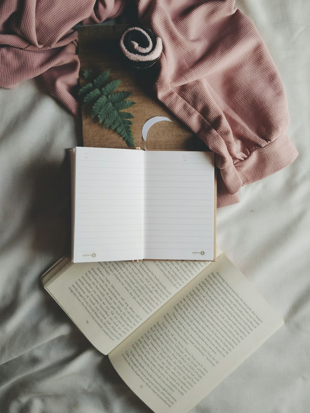 opened book and notebook on white textile