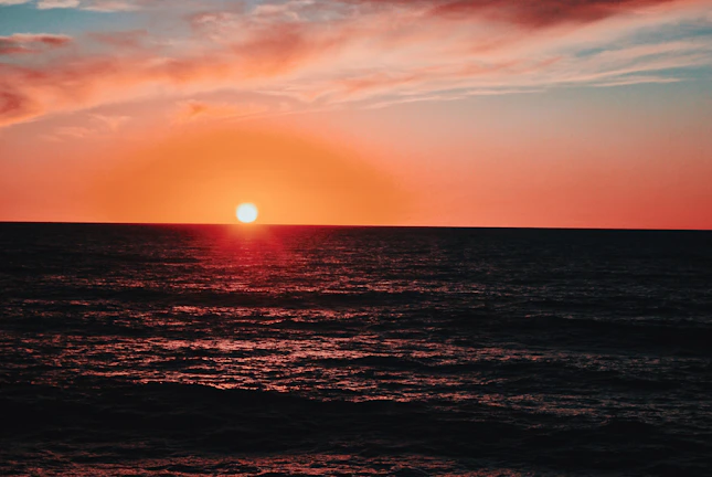 Finish line celebration with vibrant orange sunset lighting the sky over the ocean
