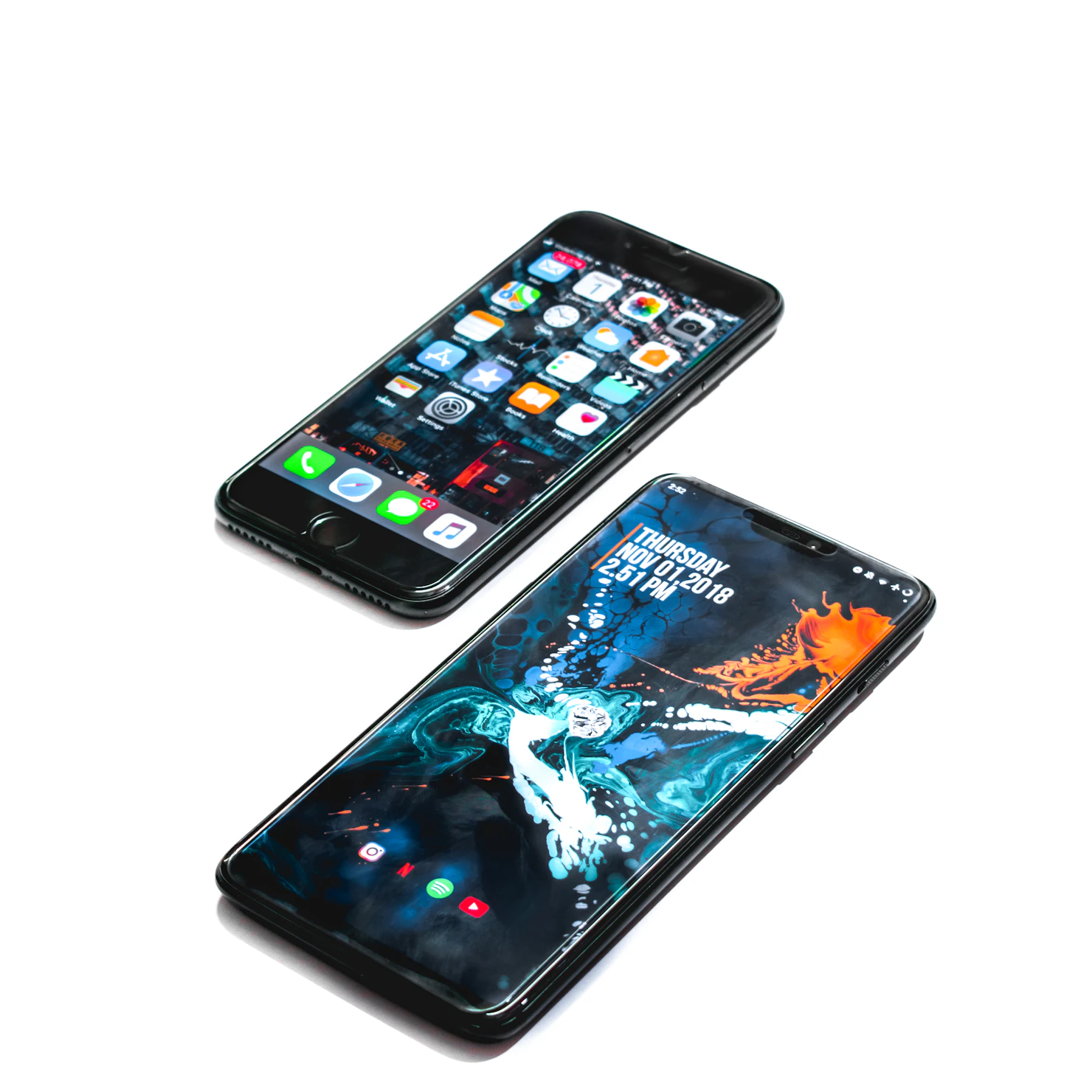 two iphones sitting next to each other on a white surface