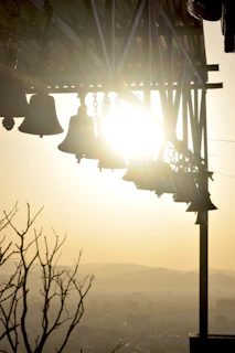 Golden temple bells hanging with soft sunlight filtering through.