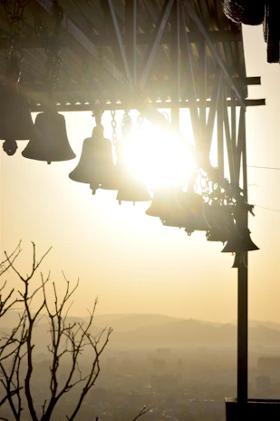 Golden temple bells hanging with soft sunlight filtering through.