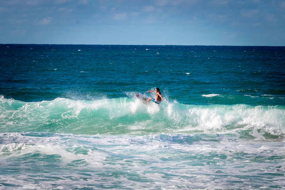 person riding surfboard facing ocean waves