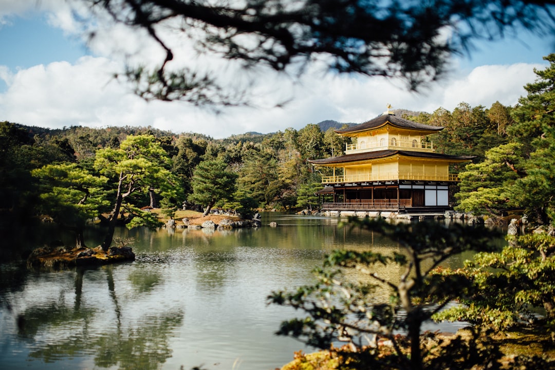 yellow building near body of water and tress