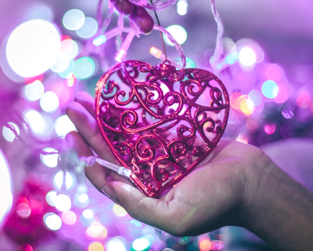 person holding purple heart pendant