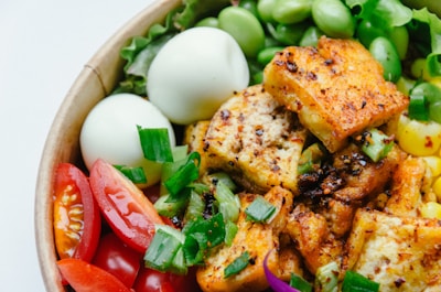A colorful bowl of fresh rice topped with grilled tofu skewers and crisp herbs.