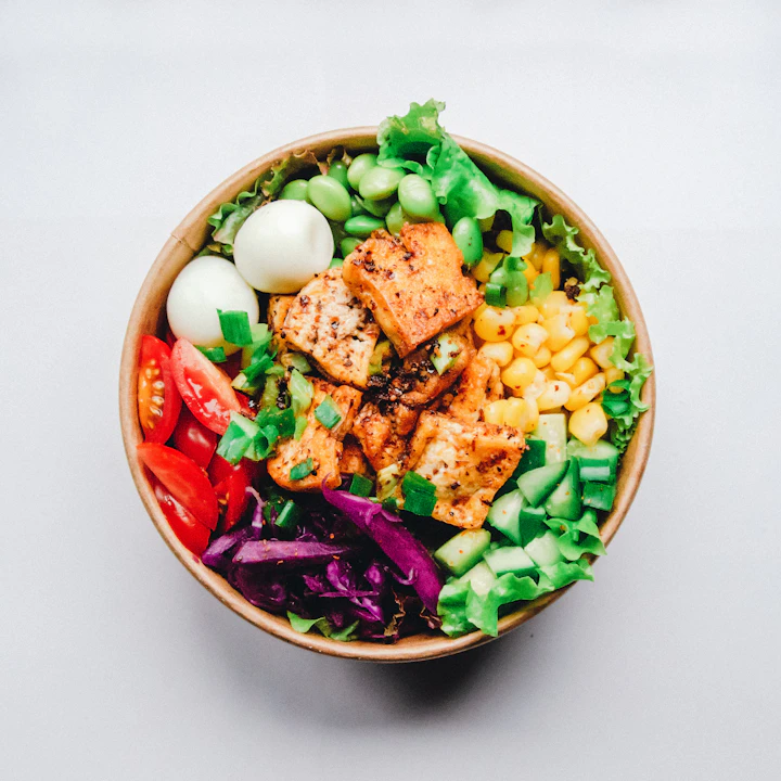 A colourful grain bowl with grilled tofu, vegetables and greens.