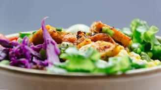 A colorful and appetizing salad bowl features a variety of fresh ingredients including purple cabbage, leafy greens, grilled chicken, and corn. The vibrant mix of colors and textures creates an inviting and healthy dish.