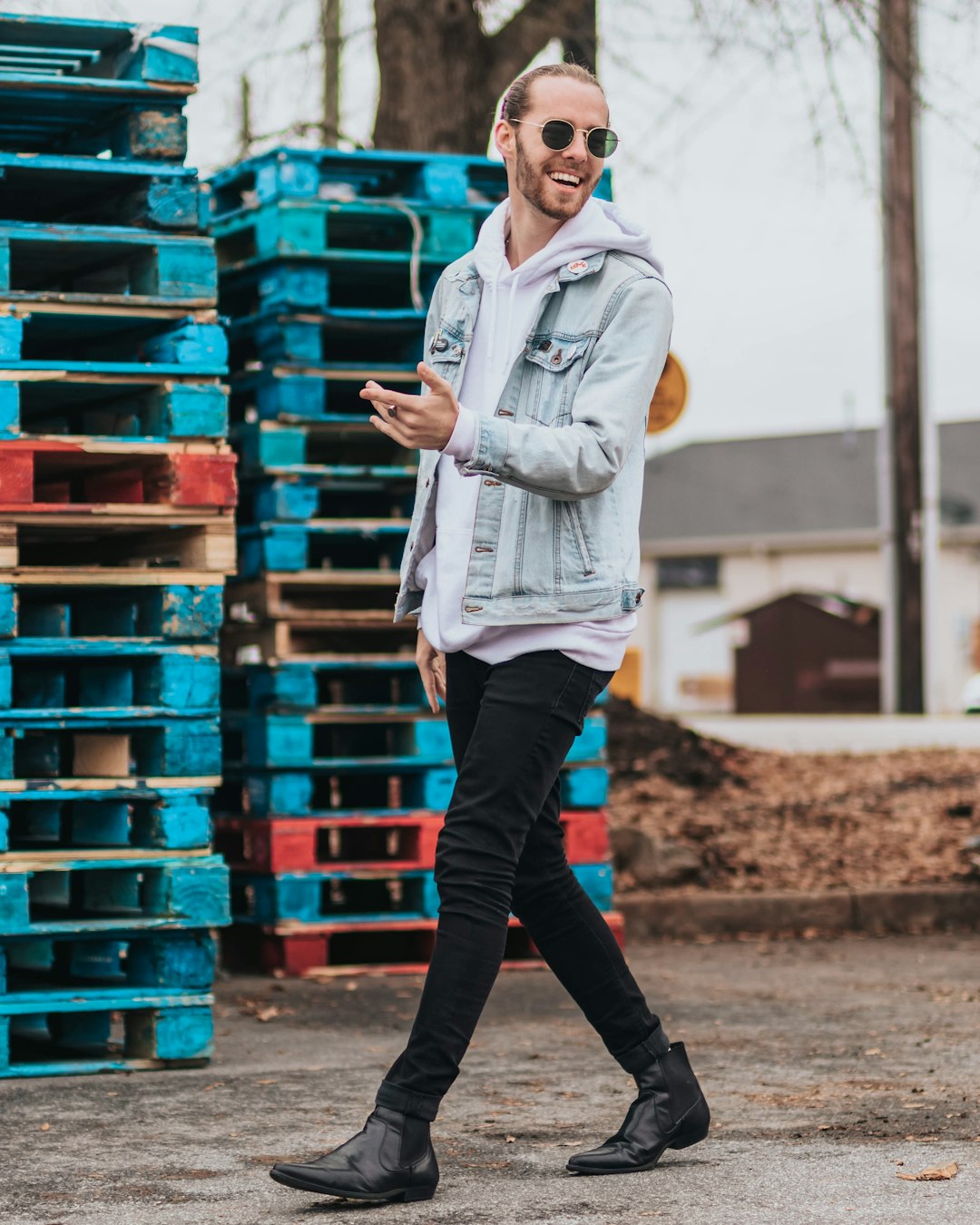 man walking beside blue wooden pallets