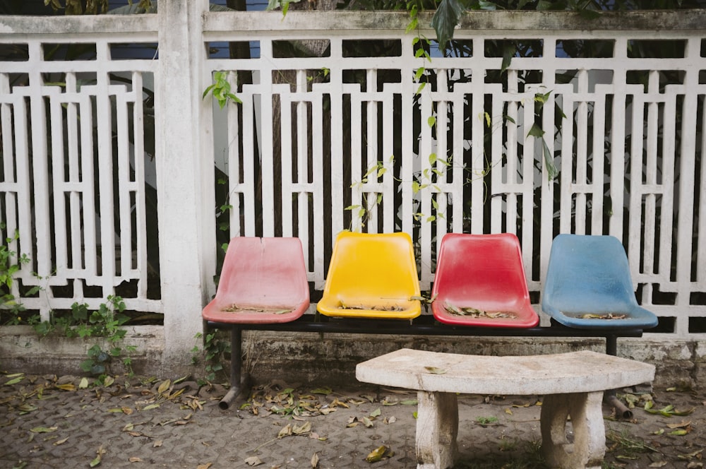 blue, red, yellow, and pink bench near white steel fence