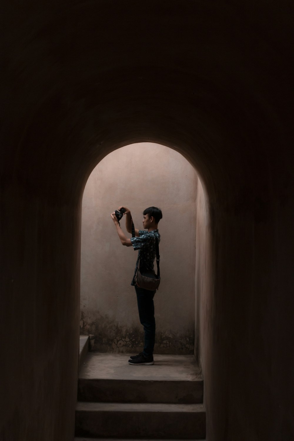 man standing beside brown wall