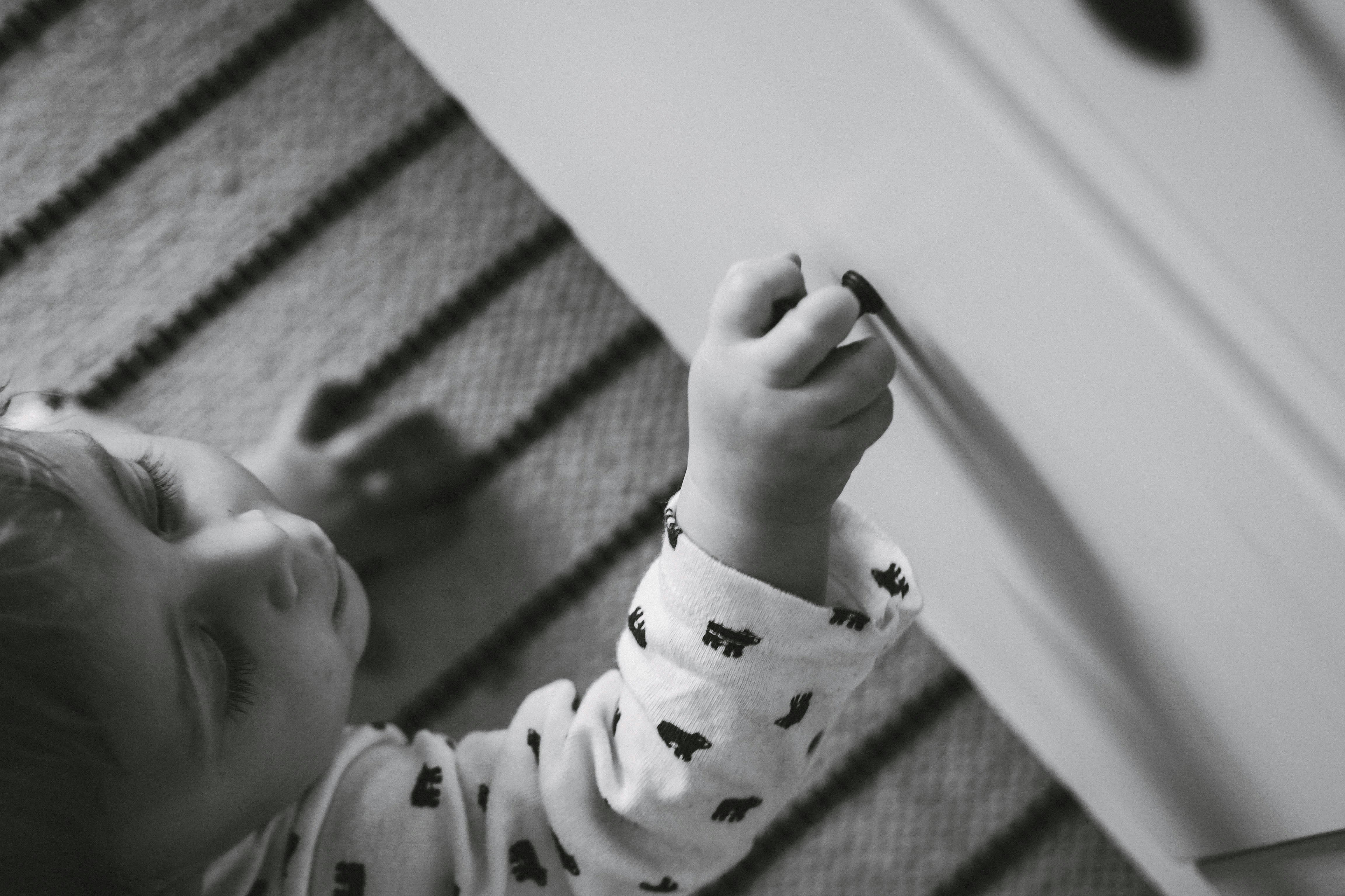 Grayscale Photo Of Baby Holding Drawer Knob Photo Free Black And