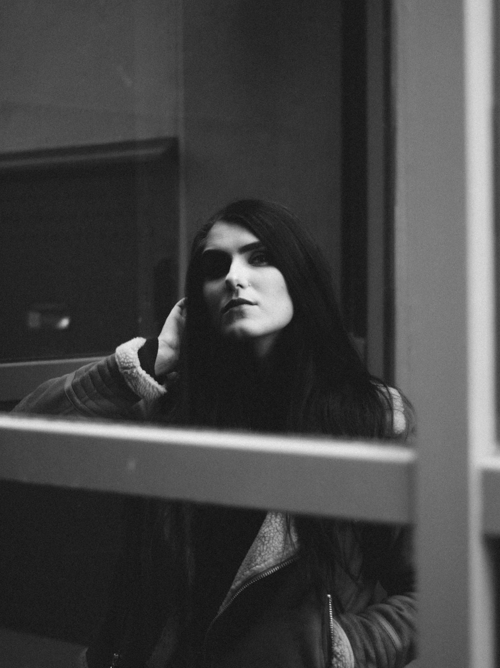 grayscale photo of woman next to window