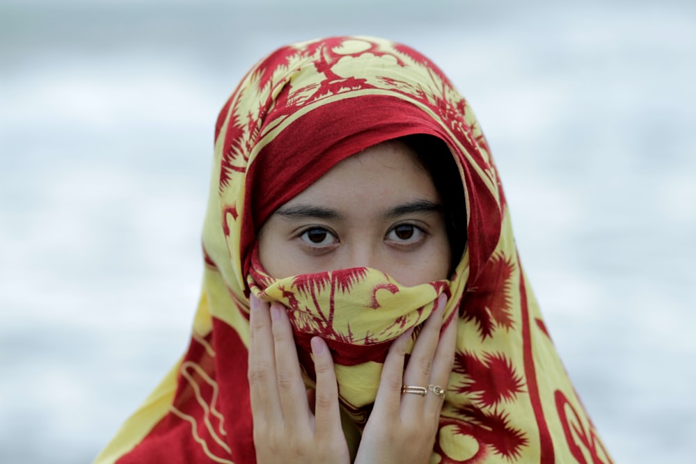 Fotografia de foco raso da mulher vestindo cocar de hijab vermelho e amarelo