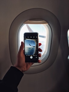 Close-up of a person holding a smartphone displaying flight booking details.