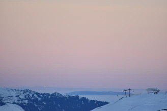 A cinematic shot of a travel creator filming a luxury mountain resort at golden hour, with soft shadows and a calm blue sky.